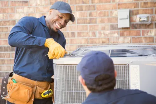 HVAC technicians working together on an outdoor air conditioning unit